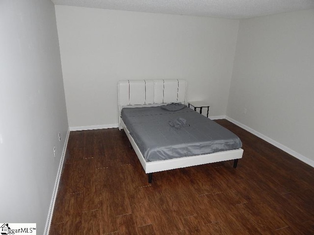 bedroom featuring a textured ceiling and dark hardwood / wood-style floors