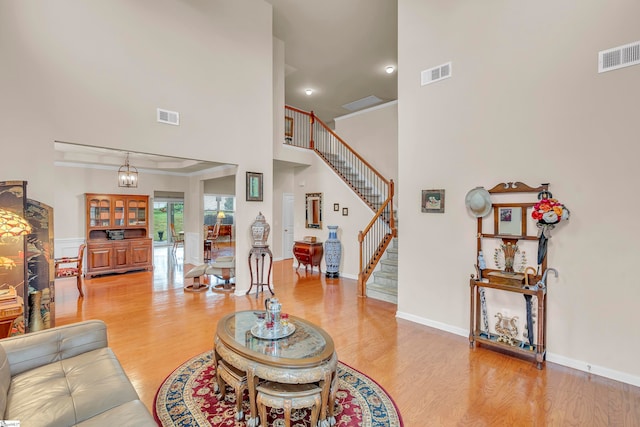 living room with an inviting chandelier, a high ceiling, and light wood-type flooring