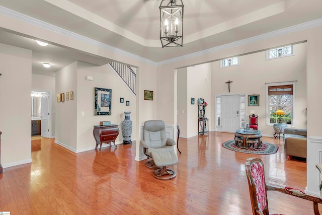 dining space featuring light hardwood / wood-style floors, an inviting chandelier, a tray ceiling, and ornamental molding