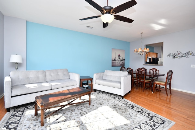 living room featuring hardwood / wood-style floors and ceiling fan with notable chandelier