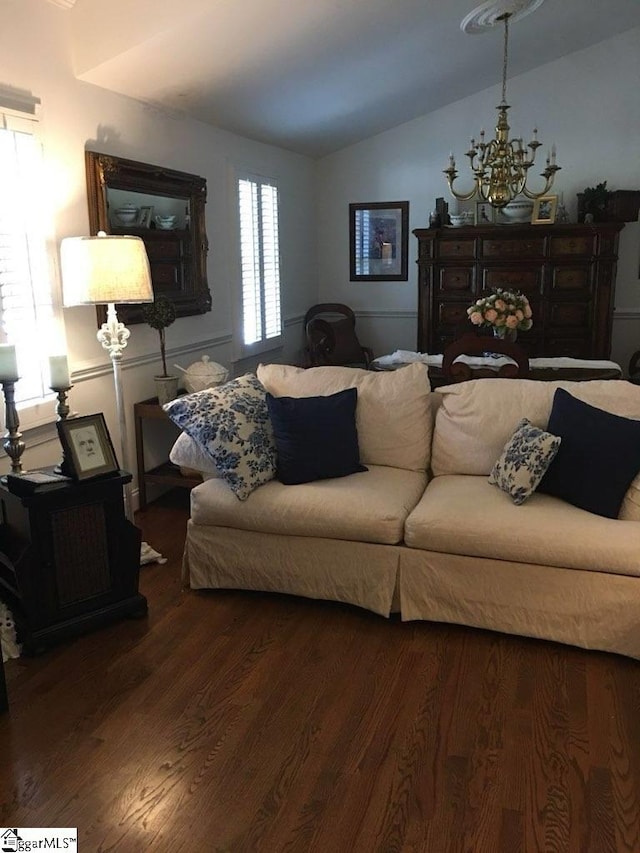 living room with an inviting chandelier, lofted ceiling, and hardwood / wood-style flooring