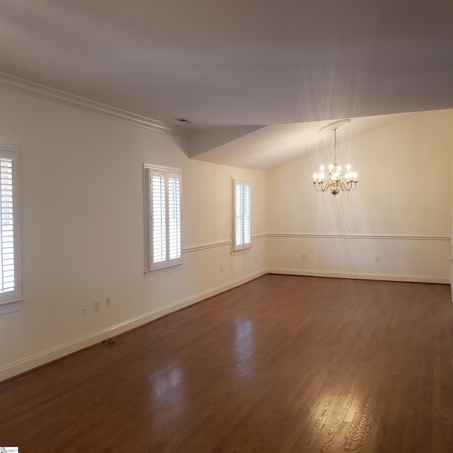 empty room with lofted ceiling, plenty of natural light, dark hardwood / wood-style floors, and a notable chandelier