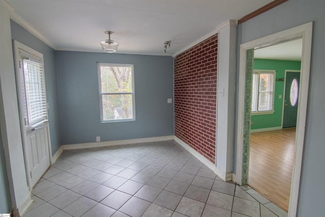 empty room with crown molding, brick wall, and light wood-type flooring