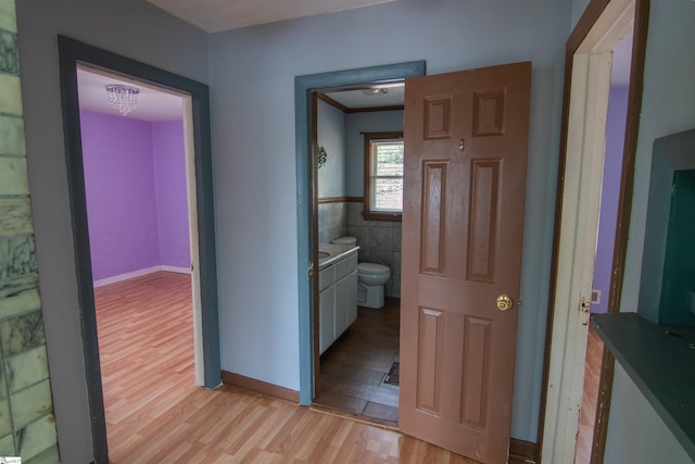 hall with light hardwood / wood-style flooring, tile walls, and crown molding