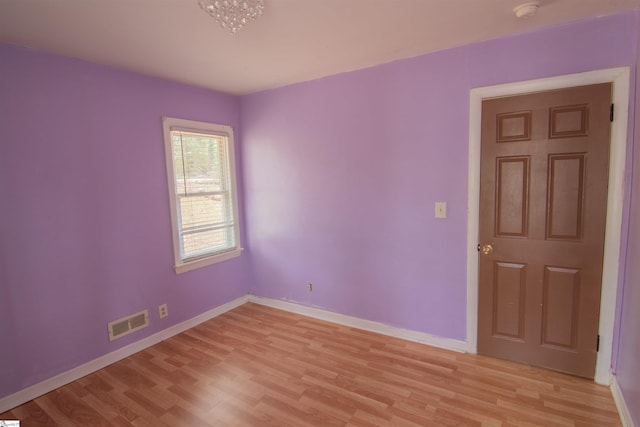 spare room featuring light wood-type flooring and an inviting chandelier