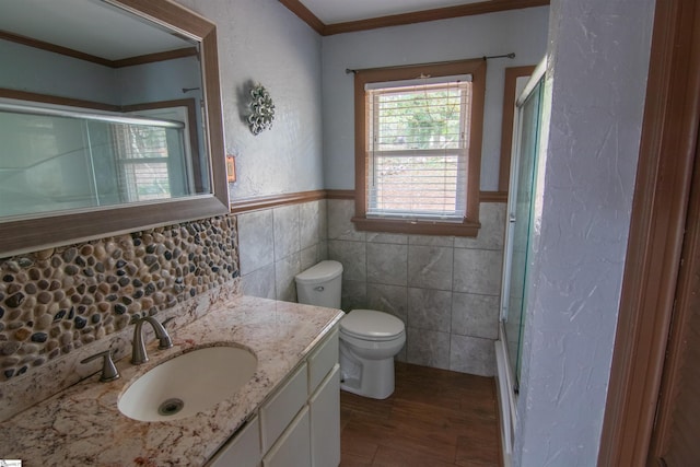 bathroom with hardwood / wood-style floors, toilet, vanity, tile walls, and ornamental molding