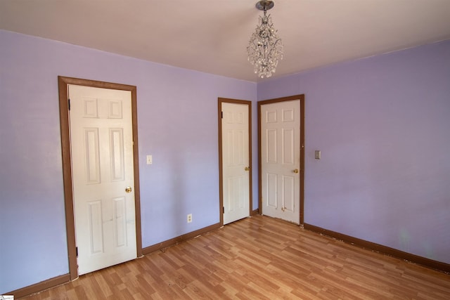 unfurnished bedroom featuring light hardwood / wood-style floors and a notable chandelier