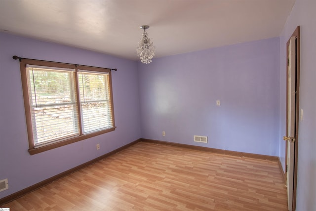 unfurnished room featuring light hardwood / wood-style floors and a notable chandelier