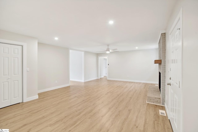 unfurnished living room with a fireplace, ceiling fan, and light hardwood / wood-style flooring