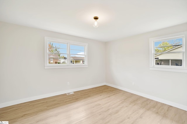 empty room with plenty of natural light and light hardwood / wood-style floors