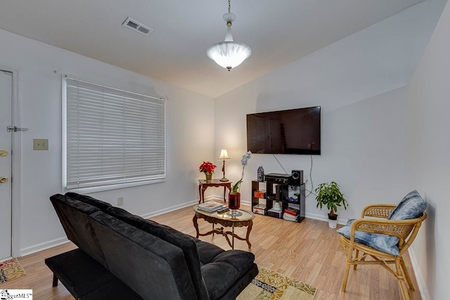 living room with light hardwood / wood-style floors and vaulted ceiling