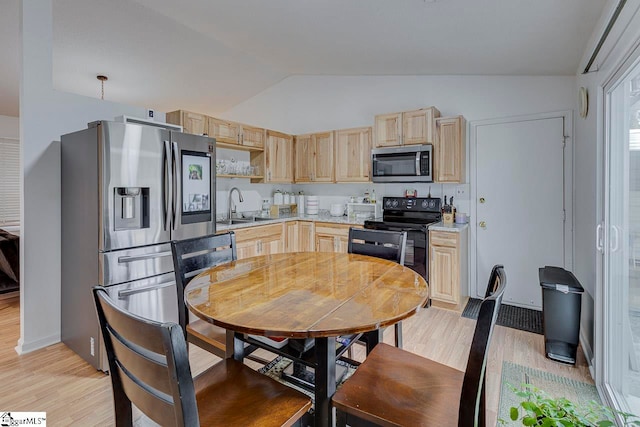 kitchen featuring sink, stainless steel appliances, lofted ceiling, light brown cabinetry, and light wood-type flooring