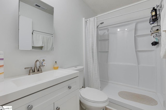 bathroom featuring vanity, toilet, a textured ceiling, and walk in shower