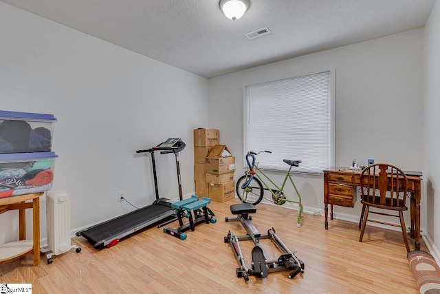 workout room with hardwood / wood-style floors, radiator heating unit, and a textured ceiling