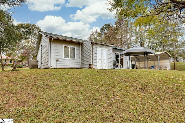 rear view of house featuring a yard and a carport