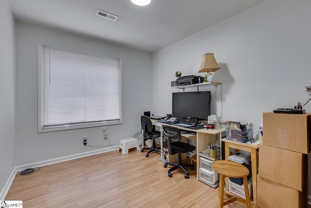 office with light wood-type flooring and a textured ceiling