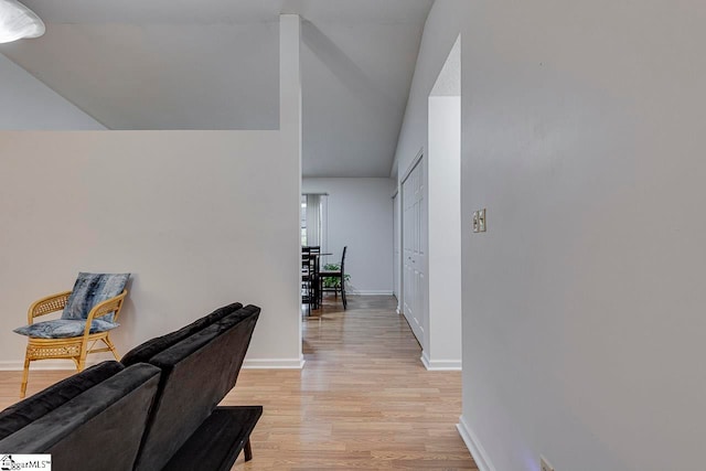 corridor with light hardwood / wood-style floors and vaulted ceiling