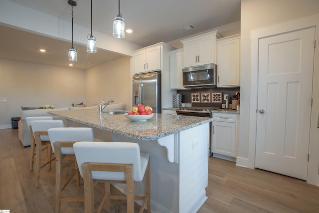 kitchen featuring a center island with sink, white cabinets, and appliances with stainless steel finishes