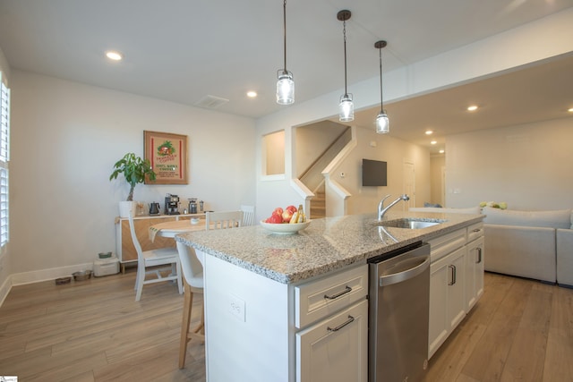 kitchen featuring white cabinets, light wood-type flooring, an island with sink, and sink