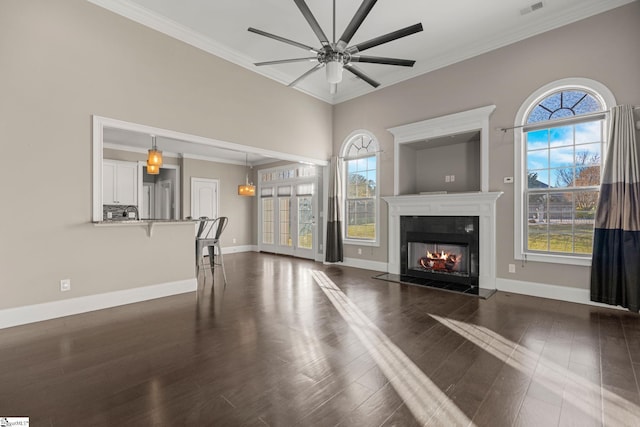 unfurnished living room featuring crown molding, dark wood-type flooring, and a healthy amount of sunlight