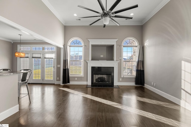 unfurnished living room with dark hardwood / wood-style flooring, ceiling fan, crown molding, and a tiled fireplace