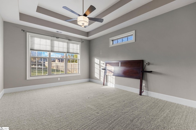 carpeted spare room featuring ceiling fan and a tray ceiling