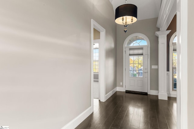 foyer entrance with dark wood-type flooring and decorative columns