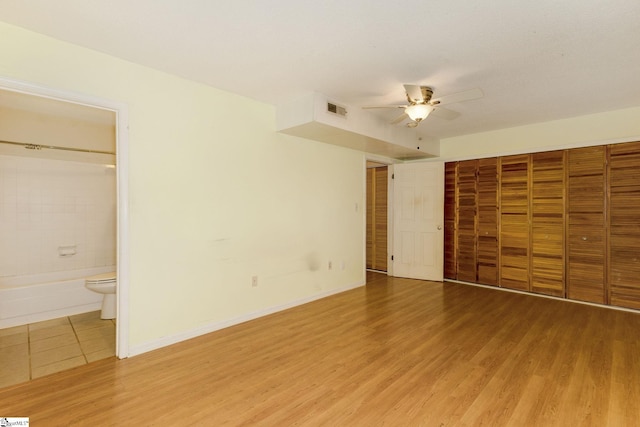 unfurnished bedroom with wood-type flooring, ensuite bath, and ceiling fan