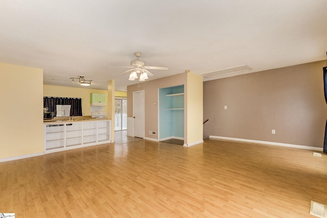 unfurnished living room with light wood-type flooring, ceiling fan, and sink