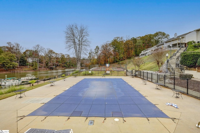 view of pool with a water view and a patio