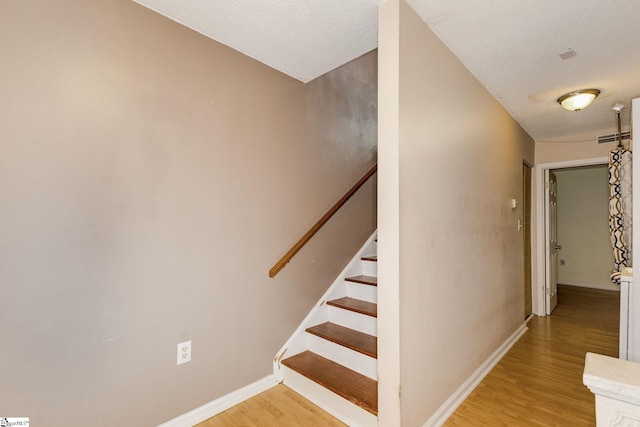 staircase with wood-type flooring and a textured ceiling