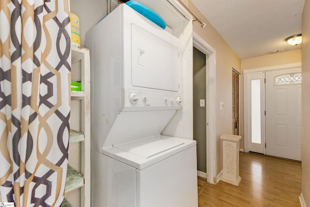 laundry area featuring stacked washer and dryer, a textured ceiling, and light wood-type flooring