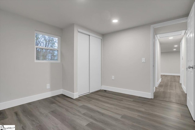 unfurnished bedroom with dark hardwood / wood-style flooring and a closet