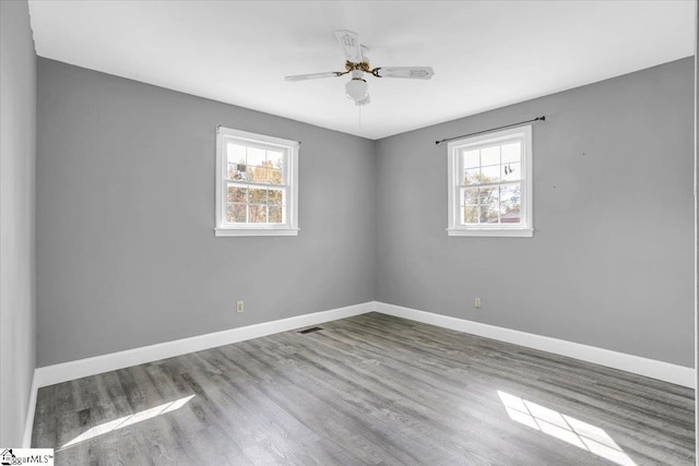 spare room featuring hardwood / wood-style floors, ceiling fan, and a healthy amount of sunlight