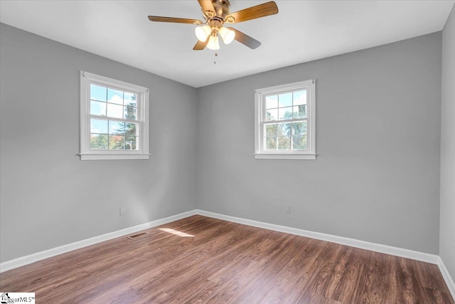 empty room with ceiling fan, a healthy amount of sunlight, and wood-type flooring