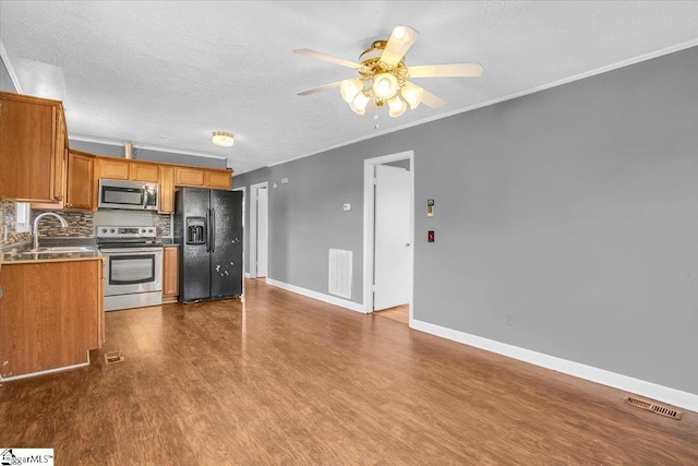 kitchen featuring sink, hardwood / wood-style flooring, ceiling fan, appliances with stainless steel finishes, and tasteful backsplash