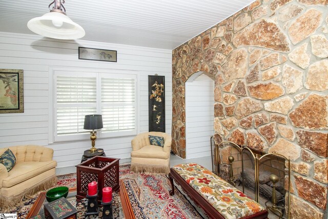 living area with a stone fireplace and wood walls