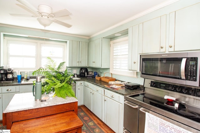 kitchen with appliances with stainless steel finishes, tasteful backsplash, dark wood-type flooring, crown molding, and white cabinetry