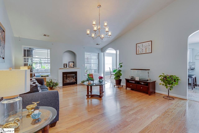 living room with light wood-type flooring, vaulted ceiling, and a healthy amount of sunlight