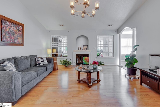 living room featuring a notable chandelier, light hardwood / wood-style floors, and a textured ceiling