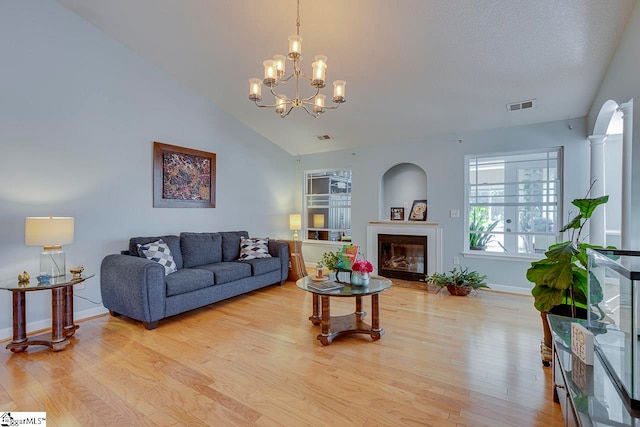 living room with light hardwood / wood-style floors, an inviting chandelier, and vaulted ceiling