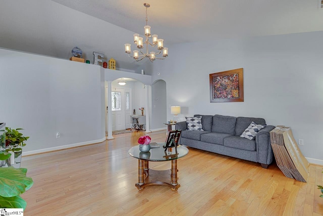 living room with a notable chandelier, high vaulted ceiling, and light hardwood / wood-style flooring