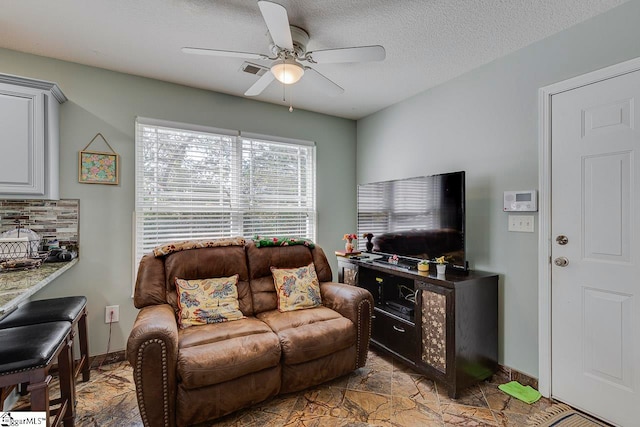 living room featuring ceiling fan and a textured ceiling