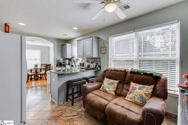 living room with ceiling fan, a healthy amount of sunlight, and a textured ceiling