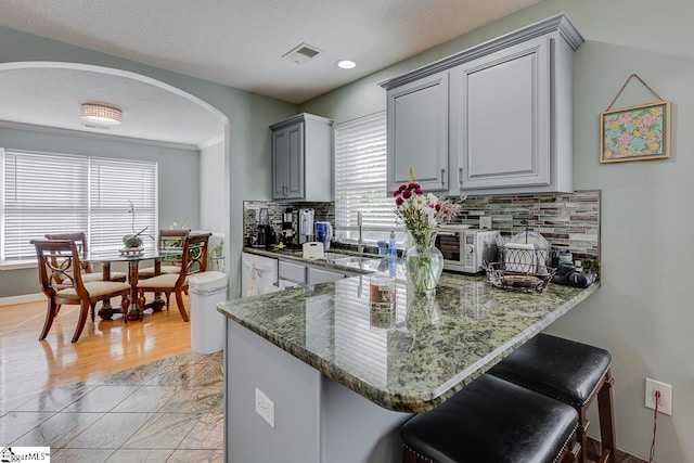 kitchen with backsplash, gray cabinetry, sink, and kitchen peninsula