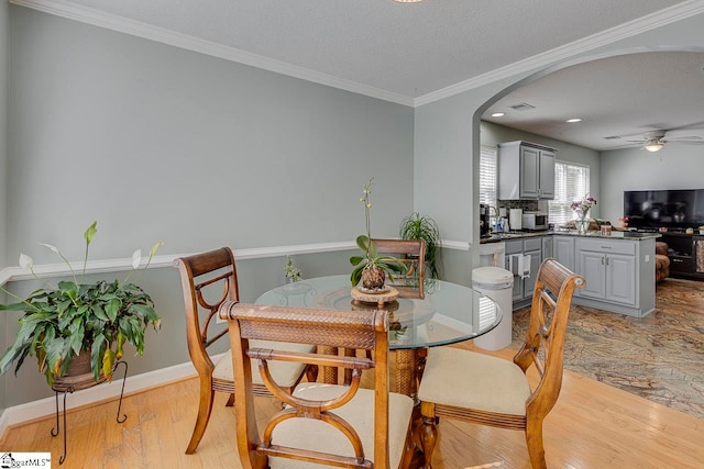 dining area featuring ceiling fan, ornamental molding, a textured ceiling, and light hardwood / wood-style flooring