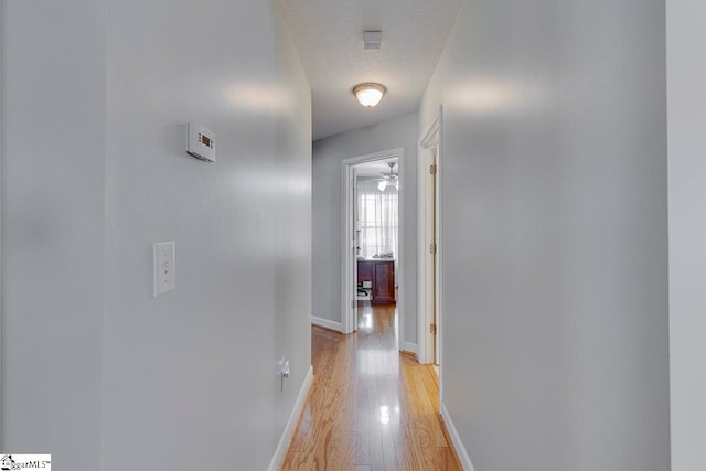 corridor featuring light hardwood / wood-style flooring and a textured ceiling