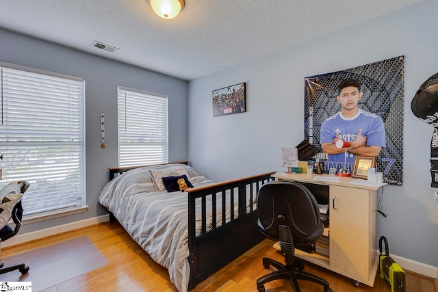 bedroom featuring a textured ceiling and light hardwood / wood-style flooring