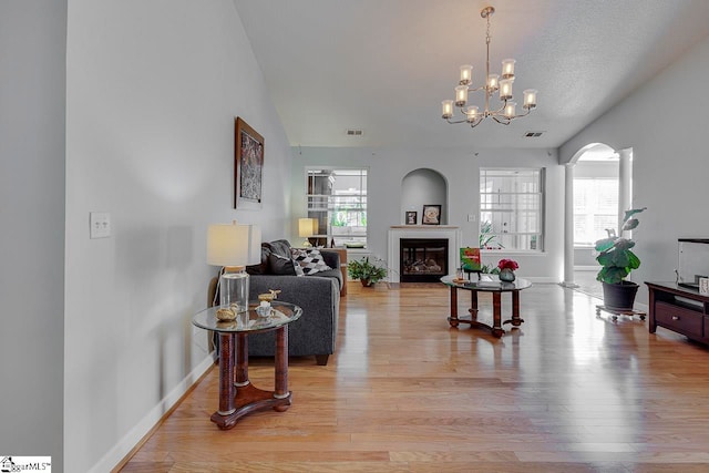 living room featuring decorative columns, a textured ceiling, vaulted ceiling, a chandelier, and light hardwood / wood-style floors