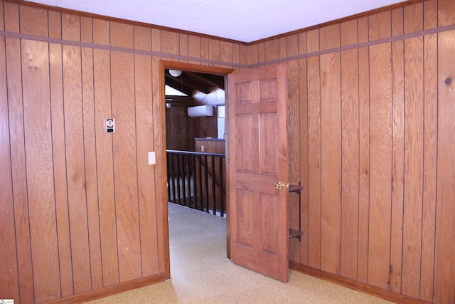 hallway featuring wooden walls and light colored carpet